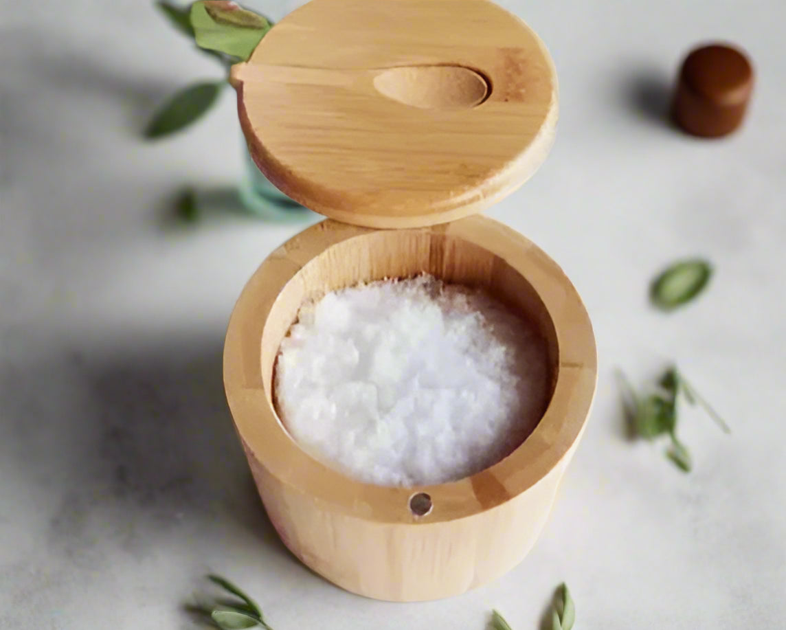 Wooden container with lid filled with white granules on a light background